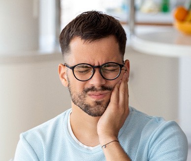 Man with black glasses experiencing toothache