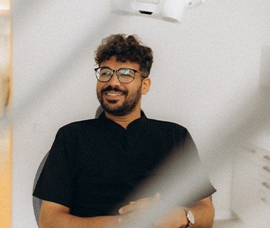 Patient with black glasses smiling in treatment chair