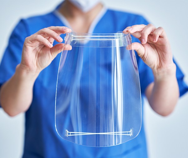 Dental team member holding a clear plastic face shield