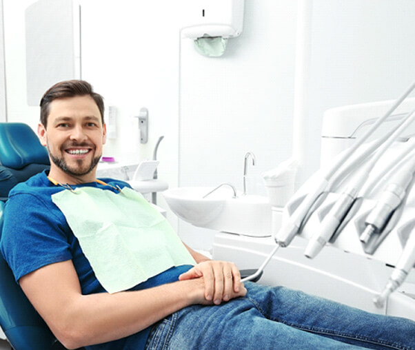 Man in blue shirt smiling while relaxed in dental chair