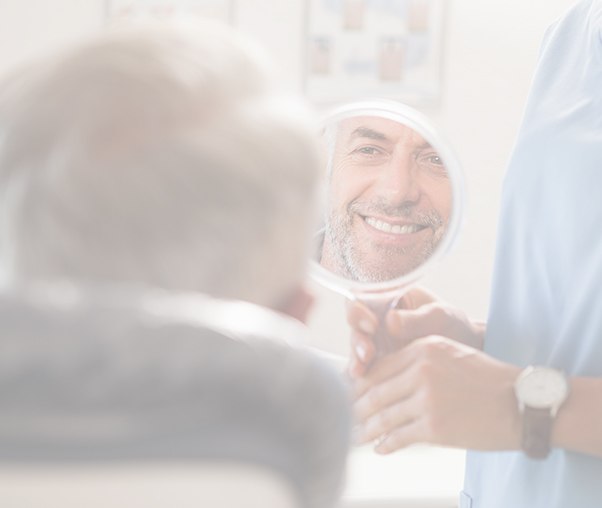 Man looking at smile after metal free dental crown restoration