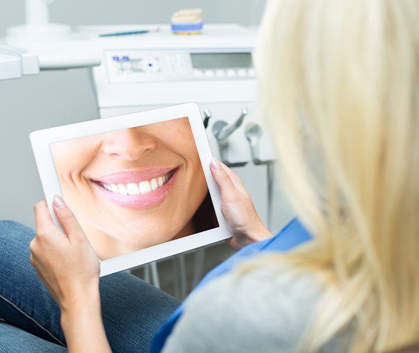 Woman looking at virtual smile design on tablet computer