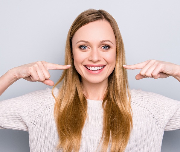 Woman smiling while pointing to her teeth