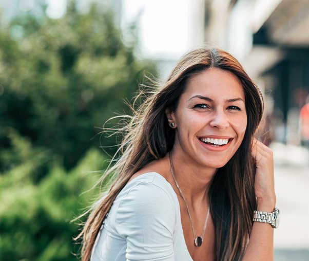 a smiling woman sitting on a bench outside