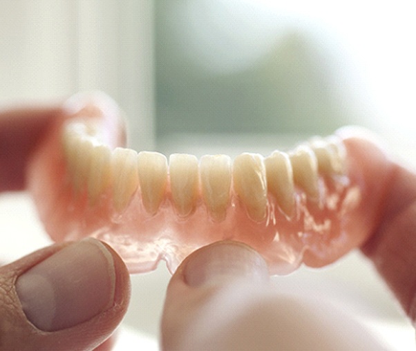 An up-close view of a lower denture created using an acrylic base and artificial teeth in Carrollton