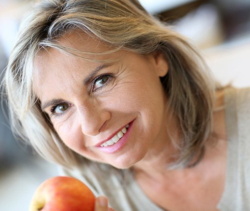 Happy senior woman holding an apple
