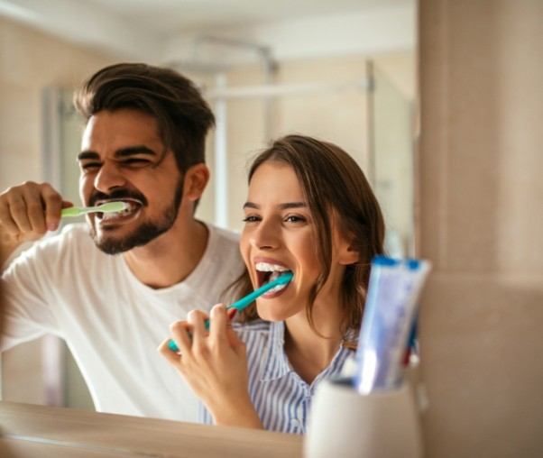 Man and woman brushing teeth to prevent dental emergencies