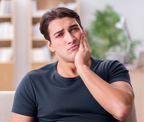 Man in need of tooth extraction holding jaw