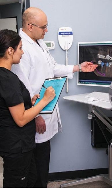 Carrollton dentist showing a dental team member a digital 3 D model of mouth with dental implants