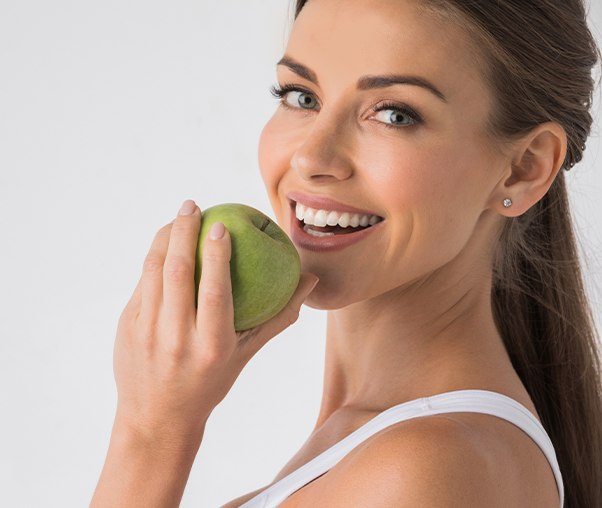 Woman eating an apple of dental implant tooth replacement