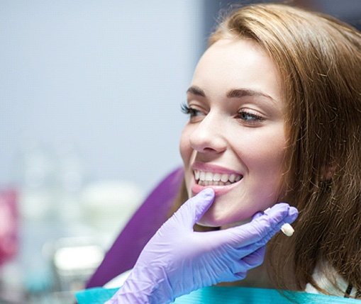 A dentist uses a shade guide to determine what color a metal-free dental crown will need to be to effectively blend in with a patient’s natural smile