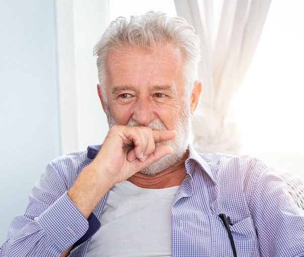 Man in need of gum disease treatment covering his mouth