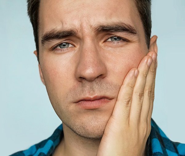 Man in need of gum disease treatment holding his cheek