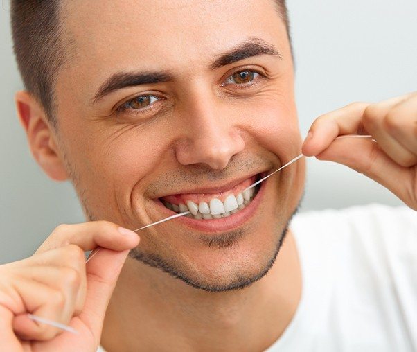 Man flossing teeth to prevent periodontal disease