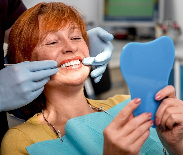 Woman looking at her smile during preventive dentistry checkup