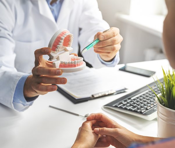 Dentist showing patient a smile model to explain root canal therapy