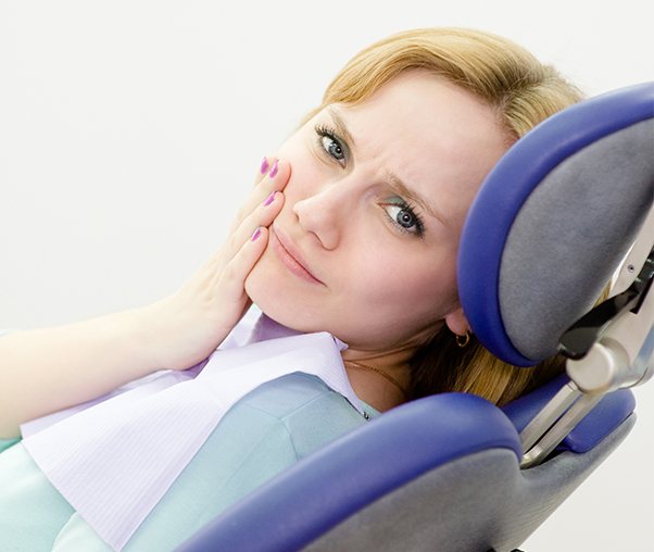 Woman in need of a root canal holding her jaw