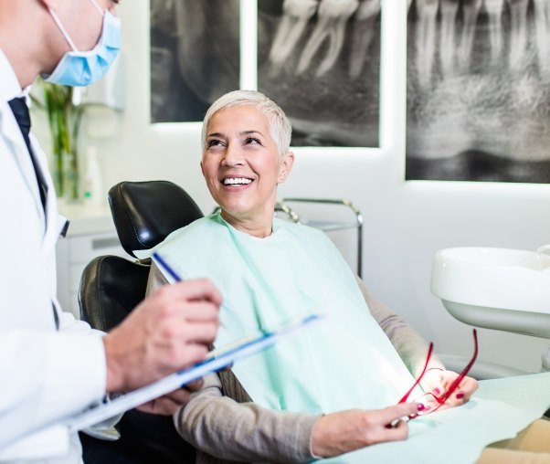 Senior woman in dental chair smiling at her dentist