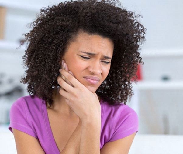 woman holding her cheek in pain