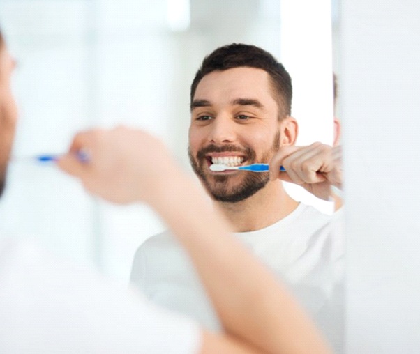 man brushing his teeth in front of a mirror