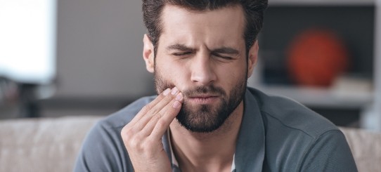 Man in need of emergency dentistry holding cheek