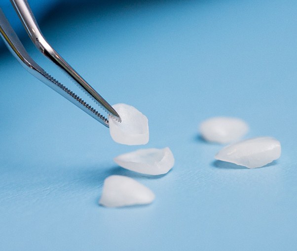 Dentist holding up veneer with tweezers