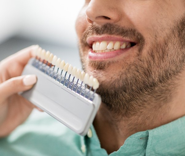 Dentist holding veneer shades up to patient's teeth