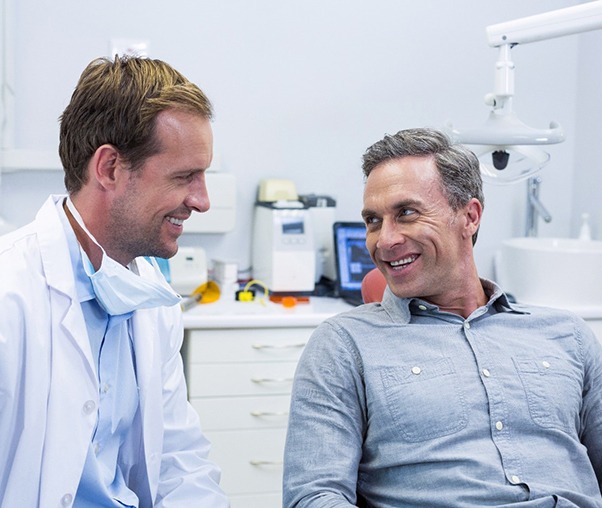 Dentist and patient smiling at each other during consultation