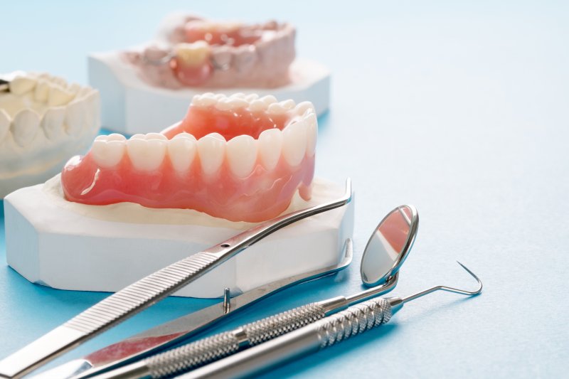 Dentures in Carrollton resting on a mouth mold with several dental instruments nearby