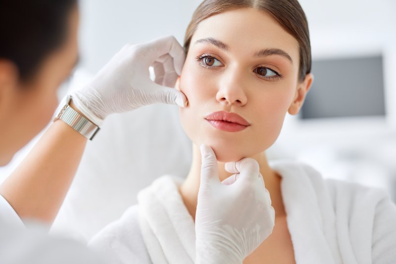 A woman having her face examined by a dentist for structural issues due to tooth loss