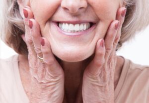 Senior woman smiling, showing off dentures. 