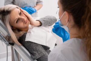 Woman suffering dental emergency in dentist's chair. 